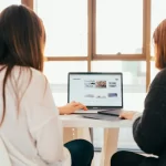 Duas mulheres olham a tela de um computador com anúncios de Marketplace