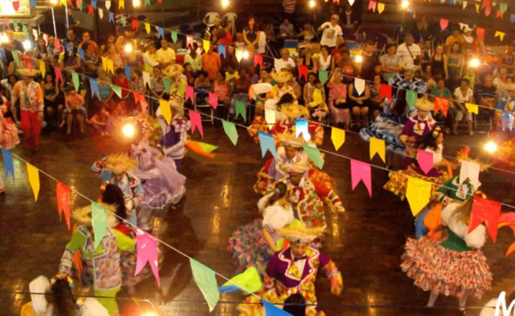 Grupo dançando quadrilha sob decoração de bandeirinhas