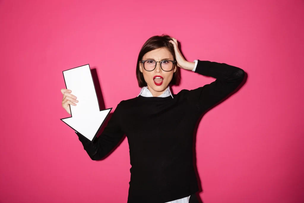 Mulher com uma mão na cabeça e outra segurando uma seta branca para baixo