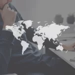 Executivo ao fundo com um mapa mundi a sua frente em preto e branco