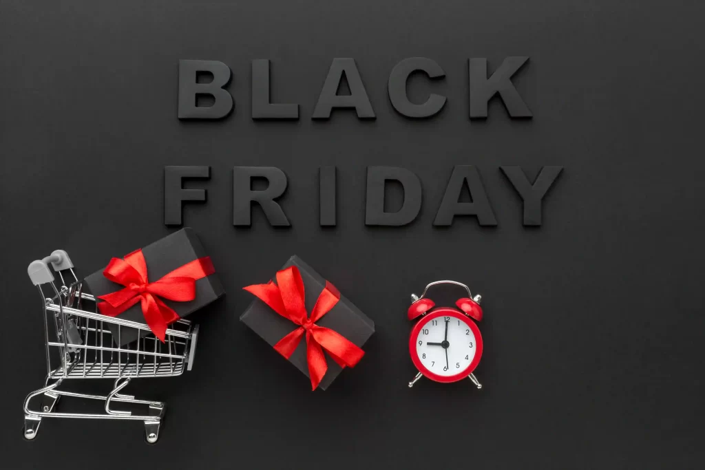 Fundo preto escrito Black Friday em cima com carrinho de compras, presentes e despertador logo abaixo