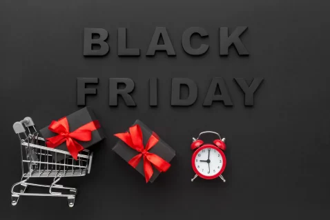 Fundo preto escrito Black Friday em cima com carrinho de compras, presentes e despertador logo abaixo