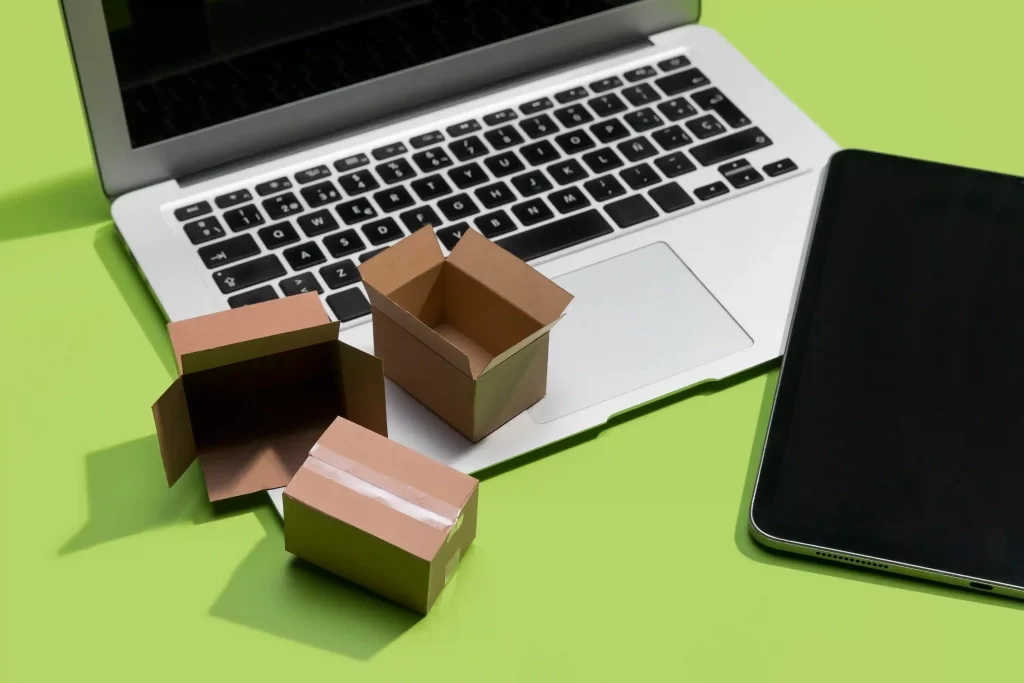 Notebook com três caixas vazias em cima ao lado de um celular em fundo verde