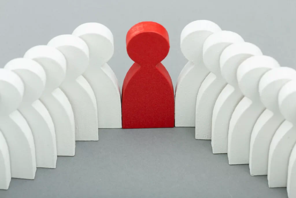 Peão vermelho, representando o vendedor entre vários peões brancos, representando a concorrência, em fundo cinza