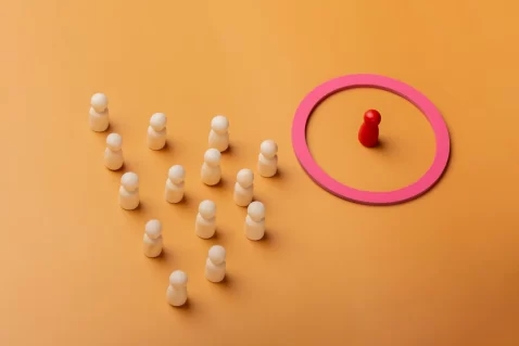 Peão de xadrez vermelho em um círculo rosa ao lado de vários peões brancos do lado de fora em fundo laranja