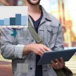 Homem usando mochila na diagonal segurando um tablet analisando microtendências