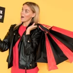 Mulher om várias bolsas de compras vermelhas e pretas com uma placa de Balck Friday em fundo amarelo