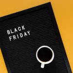 Livro preto escrito Black Friday na capa com uma lupa em cima sobre fundo amarelo