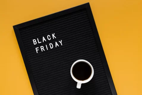 Livro preto escrito Black Friday na capa com uma lupa em cima sobre fundo amarelo