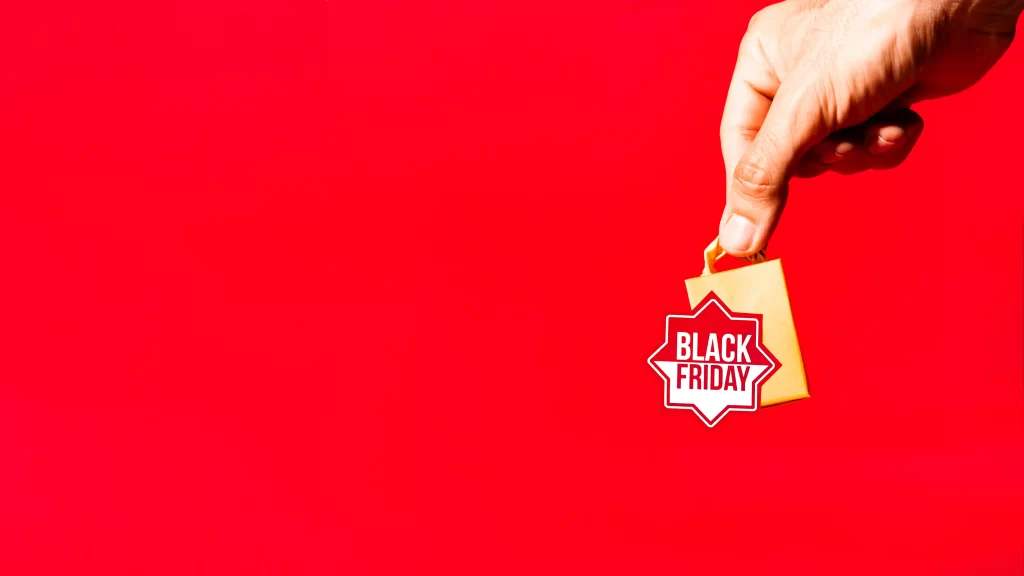 Mão segurando pequena bolsa com um selo Black Friday em fundo vermelho