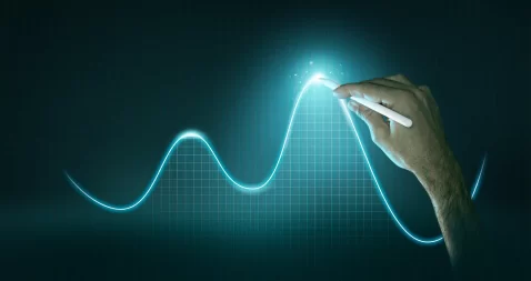 Mão de homem marcando uma onda de vendas em um gráfico preto com linha azul