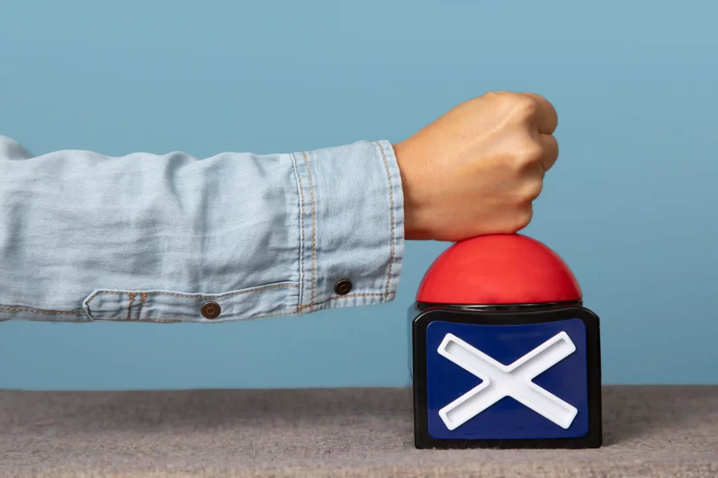 Braço de homem de jaqueta jeans batendo em um objjeto azul e vermelho com um X