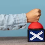 Braço de homem de jaqueta jeans batendo em um objjeto azul e vermelho com um X