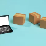 Notebook preto ao lado de várias caixas de entregar em fundo azul