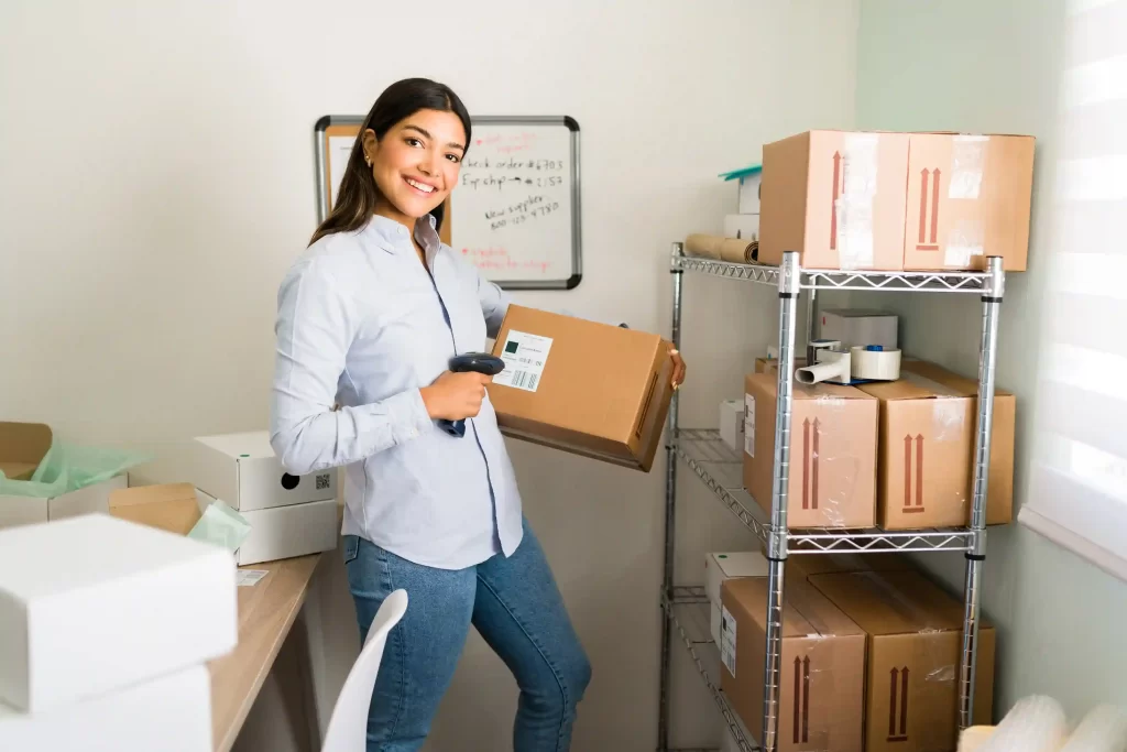 Mulher sorridente em estoque usando leitor de código de barras para registrar caixa de envio