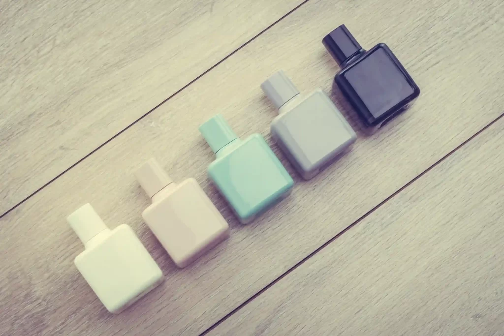 Cinco frascos de perfume alinhados em cores diferentes, representando arquitetura de variação em produtos