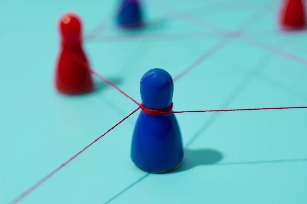 Peões de xadrez azuis e vermelhos interligados por um fio vermelho em fundo azul
