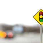 Placa de trânsito com símbolo de semáforo em vermelho, amarelo e verde, usada como metáfora de sinais para decidir se deve vender um produto