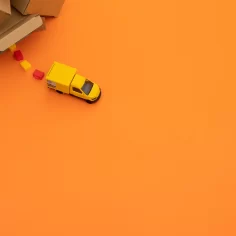 Caixas de entrega na canto alto com um caminhão amarelo do Mercado Livre saindo de perto em fundo laranja