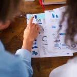 Equipe avaliando dados e gráficos em relatórios impressos, usando nowcasting de tendência para antecipar movimentos do mercado