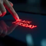 Dedo toca tela digital iluminada com as palavras “Black Friday” em vermelho brilhante