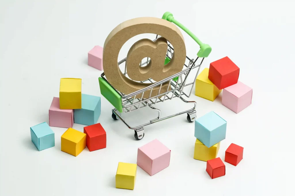 Carinho de compras com um arroba dentro ao lado de várias caixas coloridas