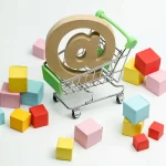 Carinho de compras com um arroba dentro ao lado de várias caixas coloridas