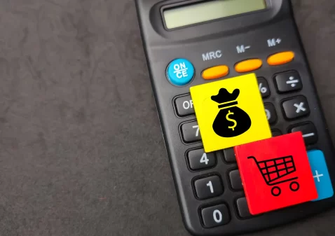 Calculadora com ícones de dinheiro e carrinho de compras, simbolizando reprecificação inteligente no comércio eletrônico
