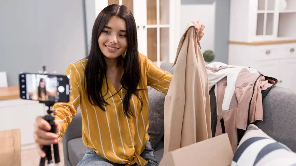 Influenciadora tirando fotos e fazendo vídeos de roupas que ela está divulgando usando o seu celular em um tripé