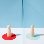 Duas figuras de madeira posicionadas frente a frente sobre círculos coloridos, representando a análise comparativa de vendedores na JoomPulse