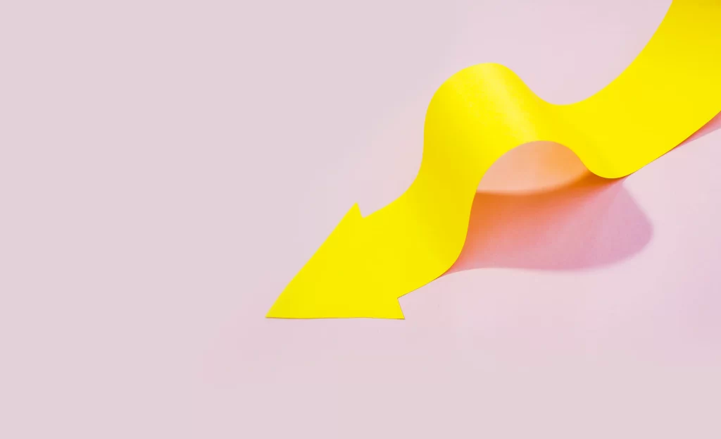 Seta amarela em curva representando a curva de precificação em fundo rosa