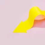 Seta amarela em curva representando a curva de precificação em fundo rosa