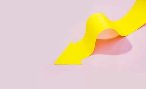 Seta amarela em curva representando a curva de precificação em fundo rosa