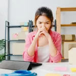 Mulher preocupada em escritório de e-commerce cercada por caixas de papelão, refletindo sobre estoque e dificuldades de venda