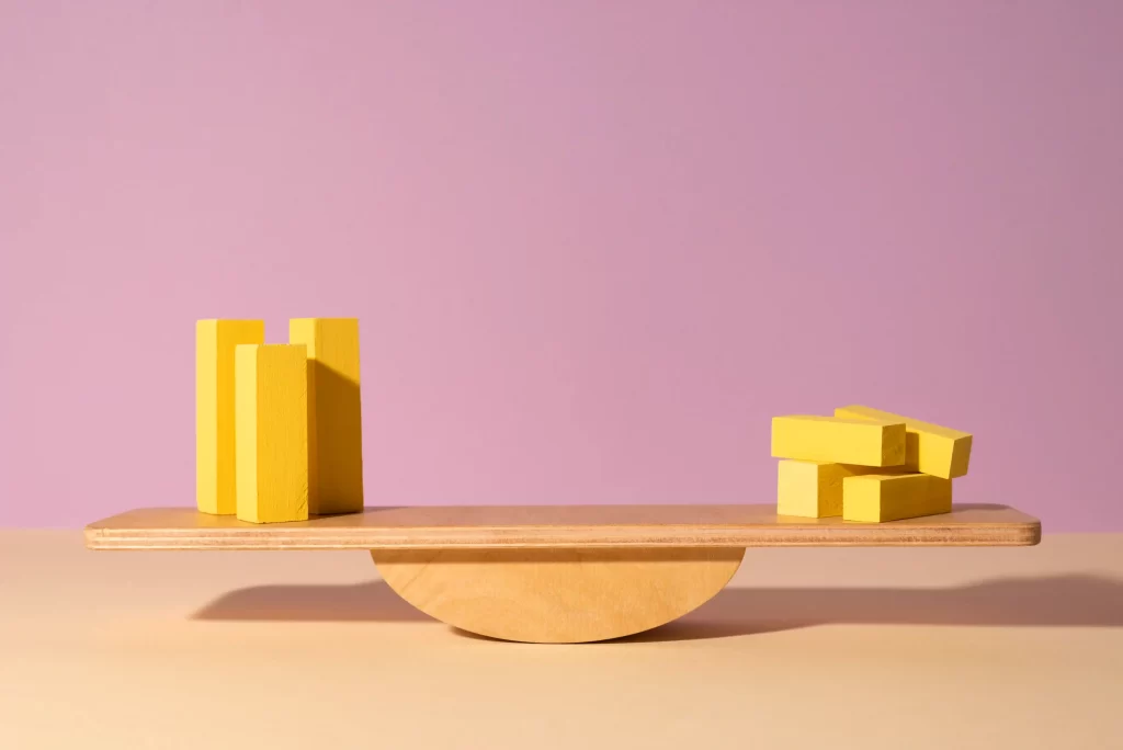 Blocos amarelos em uma gangorra de madeira, representando o equilíbrio entre produtos de entrada e produtos recorrentes