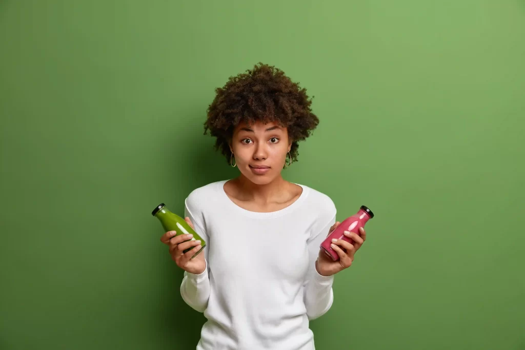 Mulher segurando duas garrafas de bebida, avaliando opções de compra