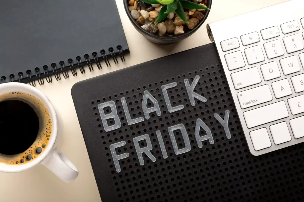 Vista de mesa de trabalho com café, teclado, caderno e placa com a frase Black Friday, simbolizando o planejamento antecipado para a Black Friday 2025