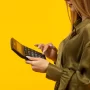 Mulher segurando uma calculadora em fundo amarelo, representando o cálculo de lucros e comissões com a Calculadora Mercado Livre da JoomPulse