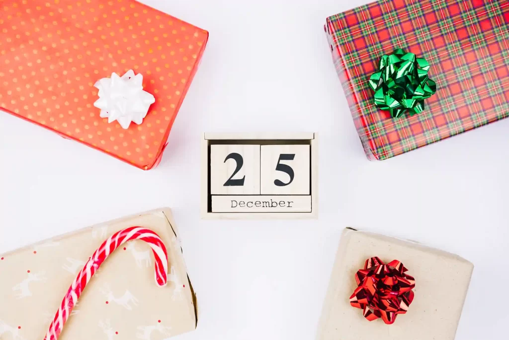 Caixa de calendário marcando o dia 25 de dezembro, cercada por presentes embrulhados e um doce em formato de bengala
