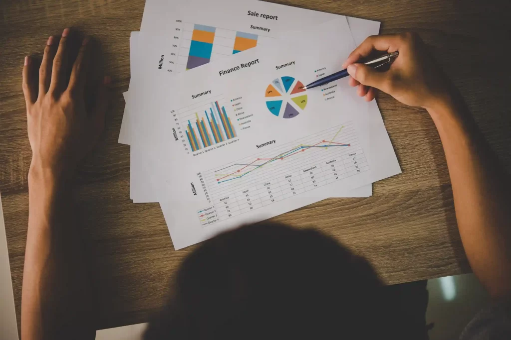 Pessoa analisando relatórios impressos com gráficos e indicadores financeiros.