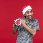 Homem sorridente usando gorro de Papai Noel e apontando para um relógio vermelho, simbolizando o clima de pressa nas vendas de última hora do Natal 2025