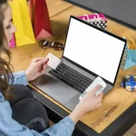 Mulher comprando pelo notebook com sacolas ao redor, ilustrando categorias que têm maior volume de vendas no desktop
