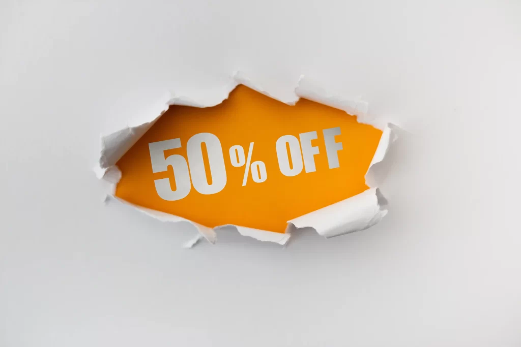 Fundo branco com papel rasgado ao centro revela a mensagem “50% OFF” em letras brancas sobre fundo laranja