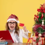 Vendedora analisando dados de visitas no Natal 2026 com seu notebook com cartão de crédito na mão