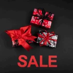 Pacotes de presente vermelhos e pretos com laços sobre fundo escuro e a palavra SALE em destaque, representando ofertas combinadas no Natal.