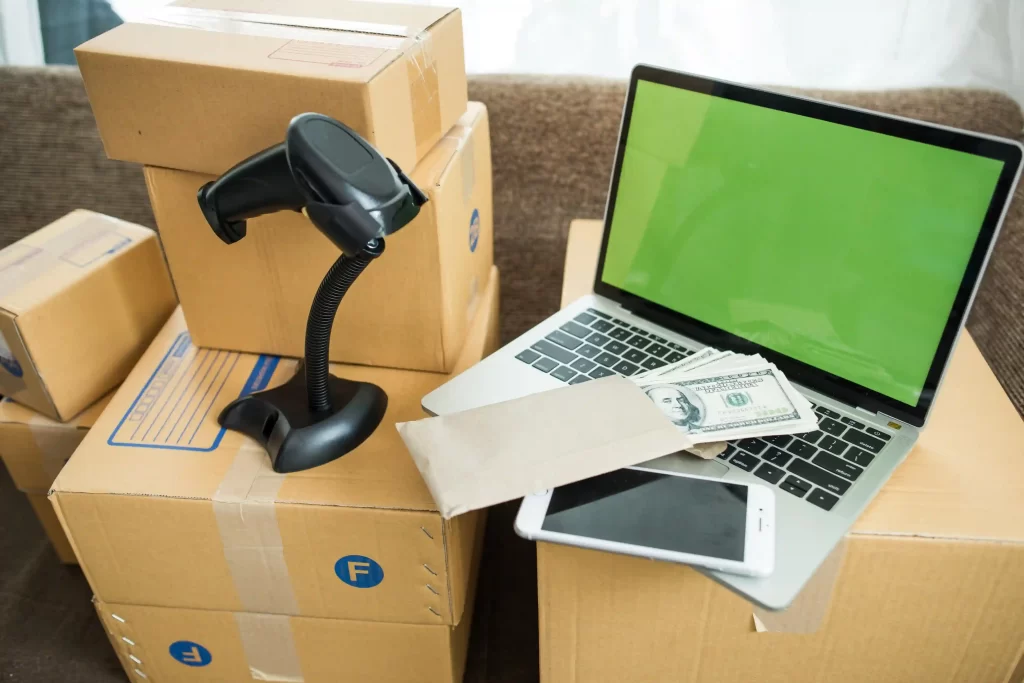 Caixas de envio, laptop e leitor de código de barras sobre a mesa, simbolizando operações afetadas pelo pico de devoluções