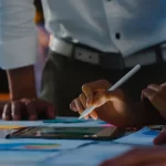 Pessoas analisando gráficos e dados em um tablet sobre a mesa, representando planejamento de janeiro e como se antecipar com decisões baseadas em dados