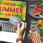 Pessoa comprando online em promoção de verão exibida no notebook, com ambiente tropical ao redor