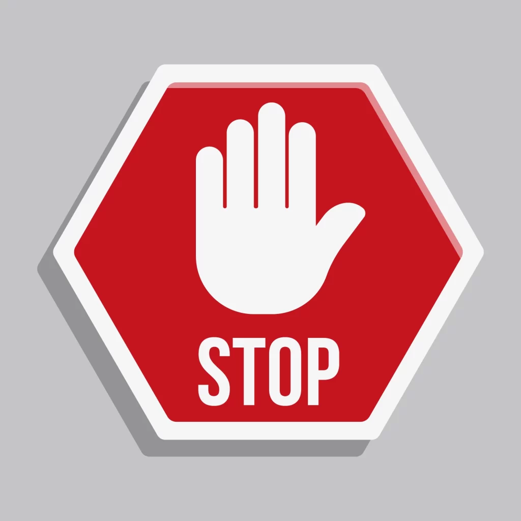 Placa de sinalização vermelha em formato octogonal com a palavra “STOP” em branco e o desenho de uma mão aberta no centro, simbolizando parada ou bloqueio
