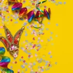 Máscara de Carnaval com confetes coloridos e serpentinas sobre fundo amarelo